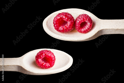 Pink vibrant raspberries on wooden spoon isolated on blach studio background. photo