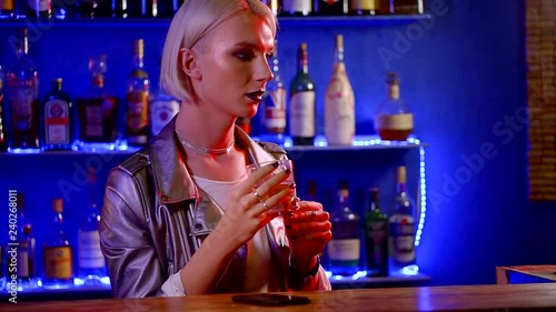 homosexual young man drinks strong alcohol in a bar in the evening. dyed leather jacket