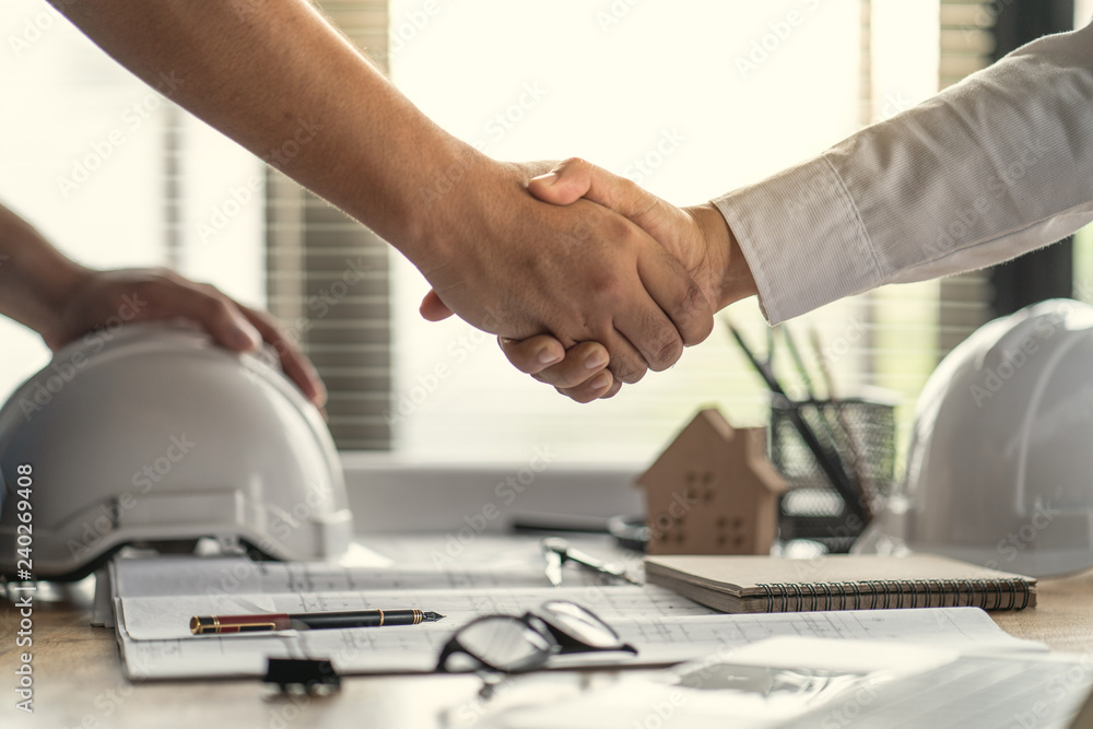 Officer teamwork is happy and shake hands to celebrate in success of finish in job planning about home building construction project Officer teamwork is happy and shake hands to celebrate in success of finish in job planning about home building construction project
