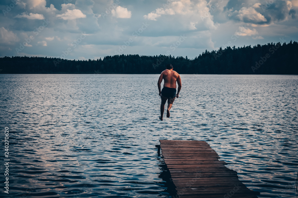 A man jumps into the water of a forest lake A man jumps into the water of a forest lake