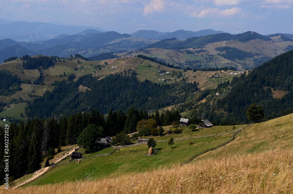 Obraz premium Dirt road high in the mountains that goes down to the village in the valley