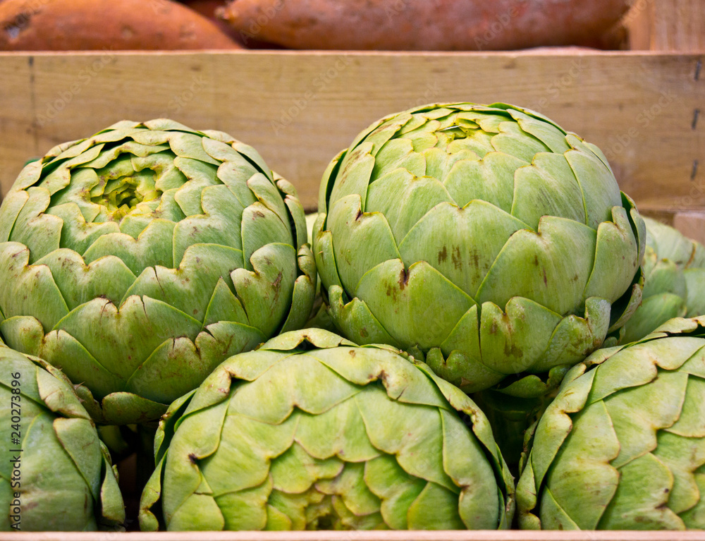 wooden box full of artichokes in French food market with sweet potatoes background wooden box full of artichokes in French food market with sweet potatoes background