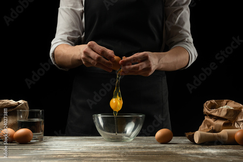 The chef works with dough, breaks the egg and whips, for the preparation of focaccia, Italian pasta, pizza or bread. Freeze in motion. The concept of restaurant business, hotel business, cooking