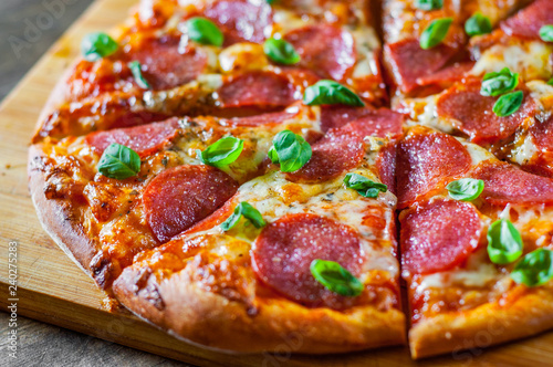 Pepperoni Pizza with Mozzarella cheese, salami, Tomatoes, pepper, Spices and Fresh Basil. Italian pizza on wooden table background