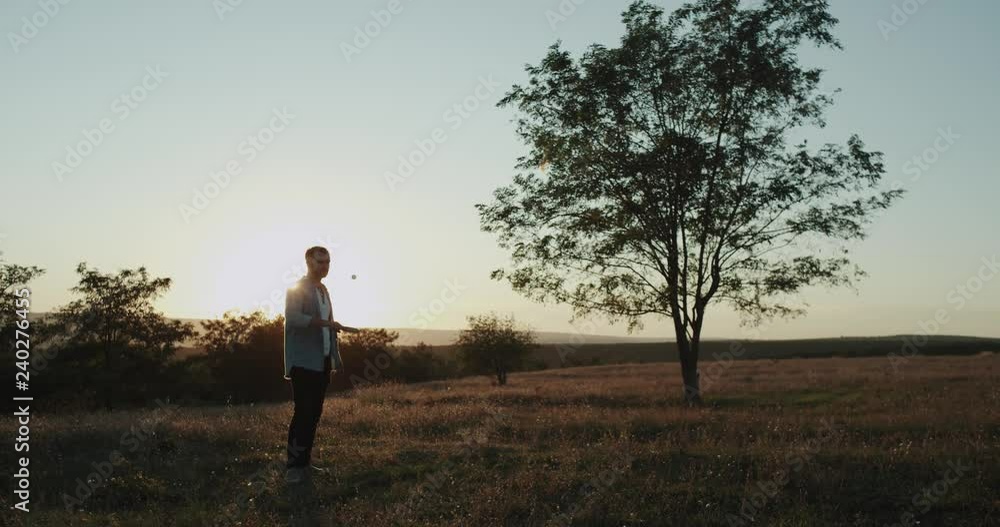 Beautiful view at nature , young charismatic man playing in the middle of field with a small racquet beat the ball. Beautiful view at nature , young charismatic man playing in the middle of field with a small racquet beat the ball.