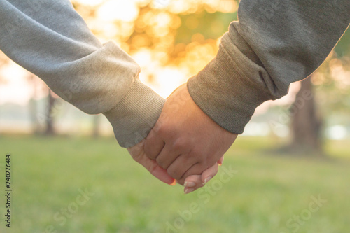 Couple holding hands at sunset. Romantic young couple in love.