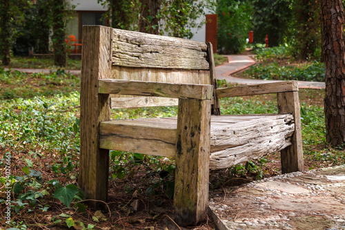 An old wooden bench spoiled by wind and rain stands in a city park