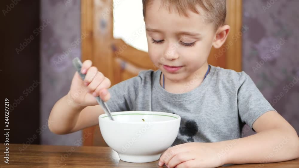 Little cute boy sits at the table and eats soup with appetite. Healthy nutrition of children. Little cute boy sits at the table and eats soup with appetite. Healthy nutrition of children.
