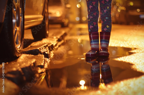 Girl in rubber boots in a puddle