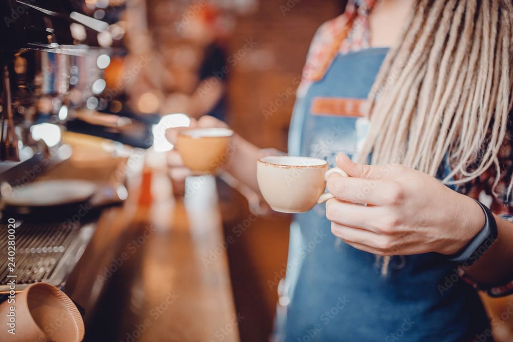 Barista girl with dreadlocks holds two small cups of espresso. She just made hot drink on coffee machine and is ready Barista girl with dreadlocks holds two small cups of espresso. She just made hot drink on coffee machine and is ready