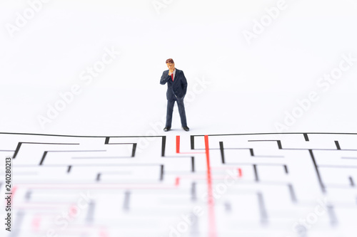 Miniature people, businessman in the labyrinth or maze figuring out the way out. Business concept, finding solution, strategic, and business opportunity.