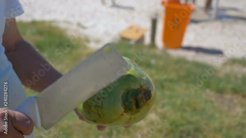 Green coconut peeling and shelling with heavy chop knife for juice on the beach, Rio de Janeiro