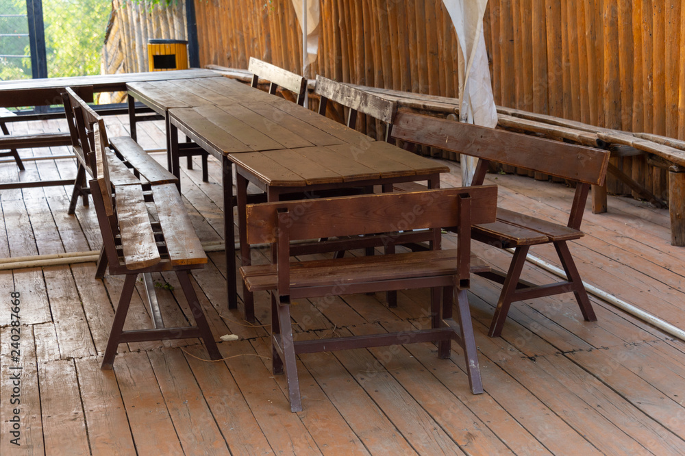 The interior is a beautifully decorated modern outdoor wooden pavilion with a ceiling and walls, a massive table, benches. Luxury lifestyle concept The interior is a beautifully decorated modern outdoor wooden pavilion with a ceiling and walls, a massive table, benches. Luxury lifestyle concept