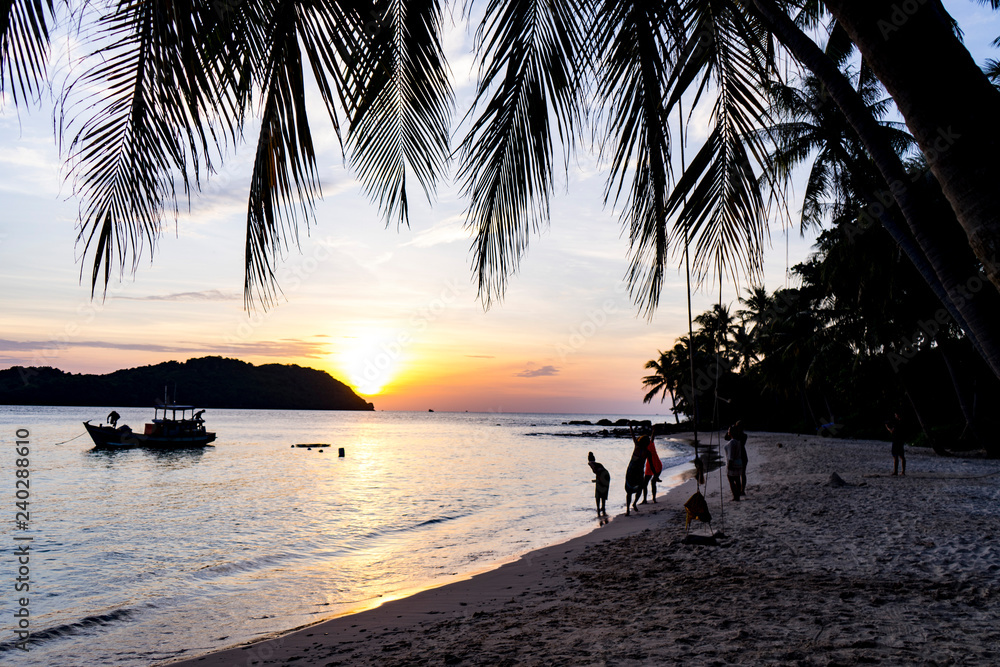 Beautiful charming sunset by the sae on the beach of Phu Quoc island with beautiful view of palms,mountains and orange sky