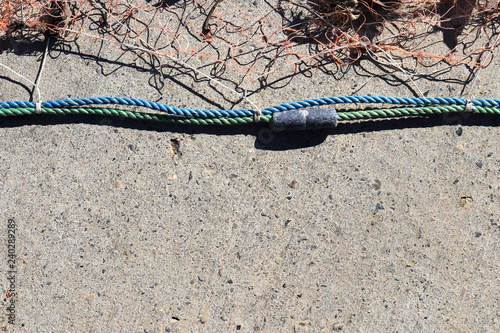 Nautical marine background. Fishnet with sinker on rope.