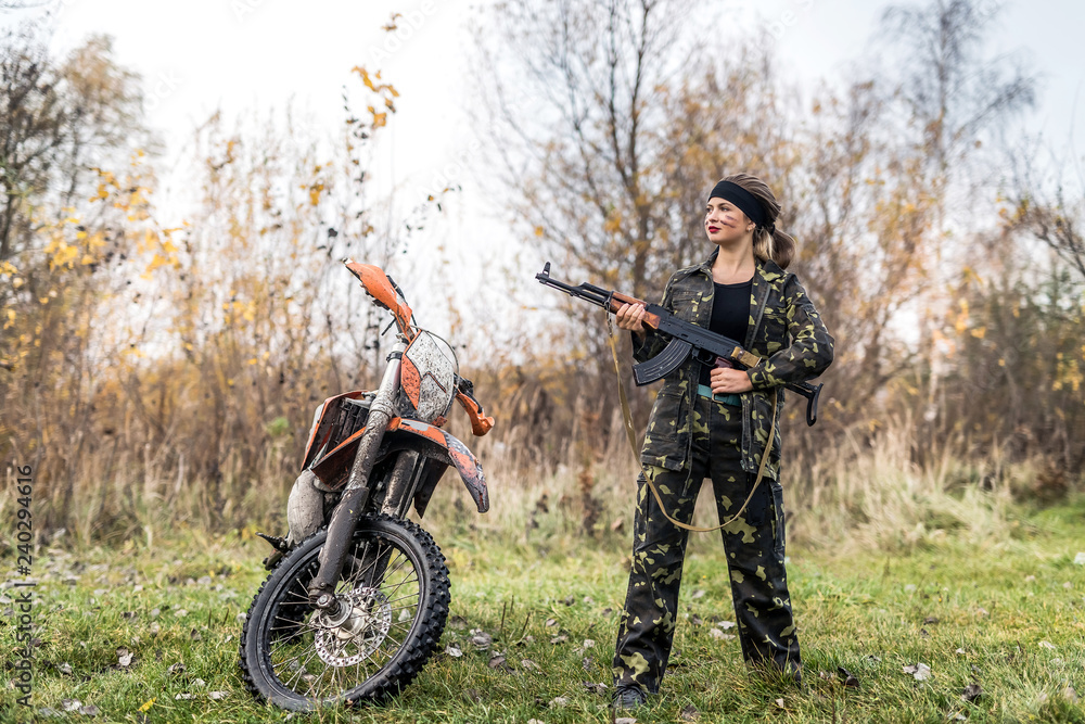 Woman soldier posing with rifle and motorcycle