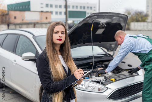 Woman making some notes while worker making diagnostic