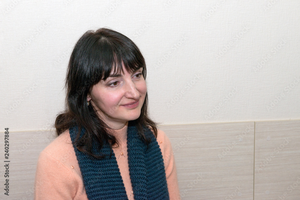 Close-up portrait of mature adult woman on light wallpaper background.