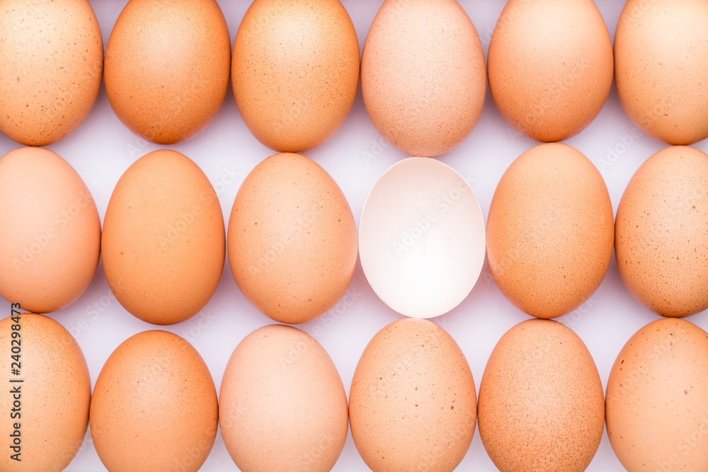 Rows of brown organic eggs and one opened, empty egg on a white background. Rows of brown organic eggs and one opened, empty egg on a white background.