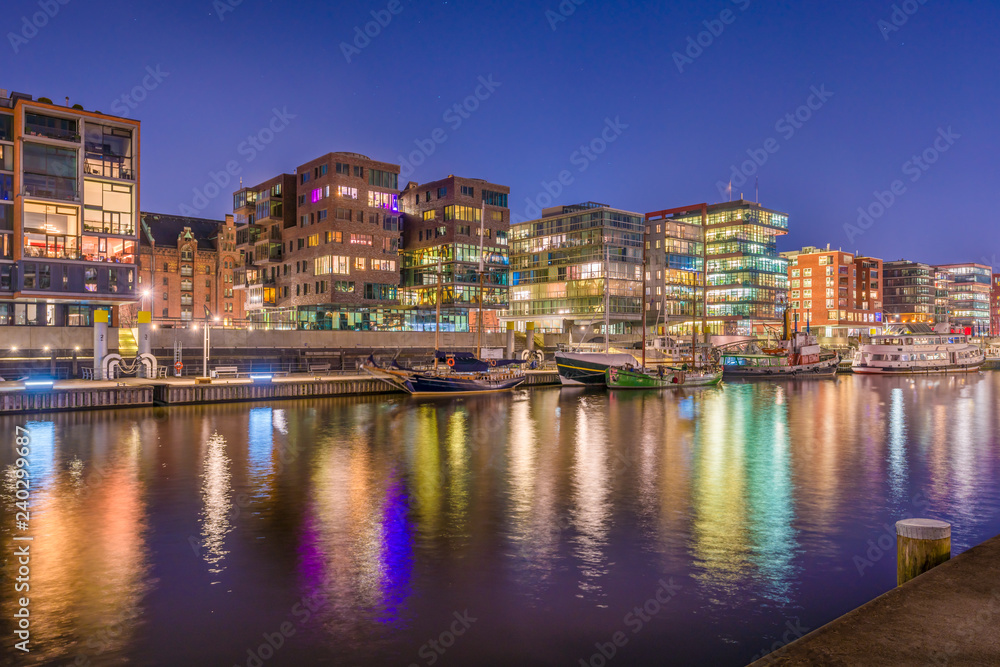 The Harbor District (HafenCity) in Hamburg, Germany, at night. A view of the Sandtorkai across the traditional port Sandtorhafen.