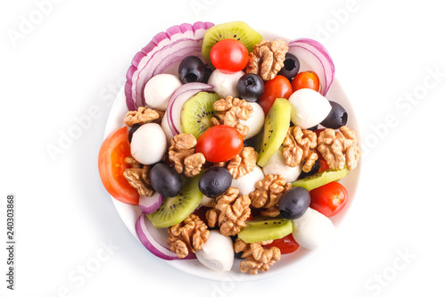 Salad with cherry tomatoes, mozzarella cheese, black olives, kiwi, and walnuts isolated on white background.