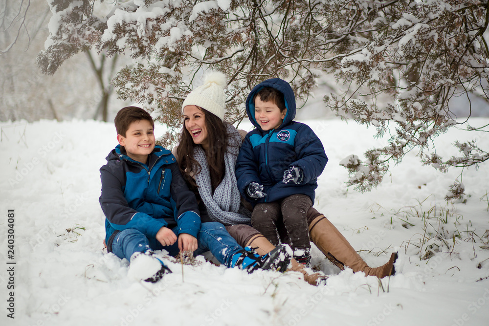 Beautiful family photo of mom with her two sons enjoying winter time.