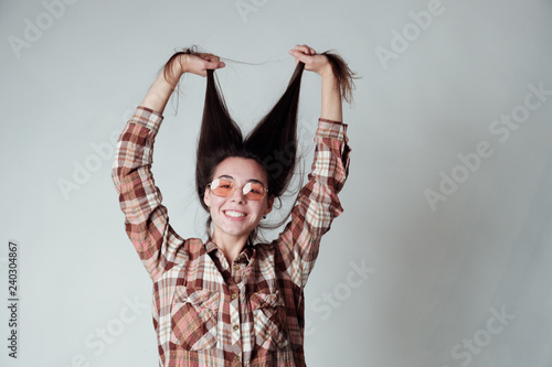 Cute young brunette girl in lumbercheck check shirt playing with hair photo