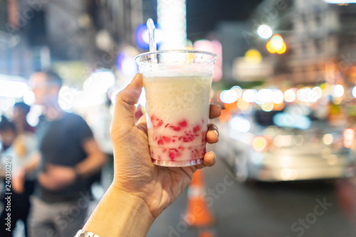 Chinese dessert called Mock Pomegranate (Ruby) on hand holding with blurry China Town background, Bangkok Thailand.