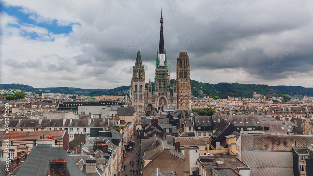 Towers and front façade of the Rouen Cathedral over medieval street and buildings of the city center of Rouen, France