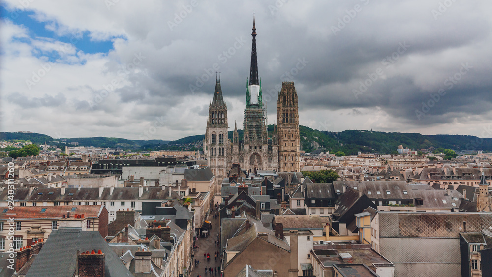 Fototapeta premium Towers and front façade of the Rouen Cathedral over medieval street and buildings of the city center of Rouen, France