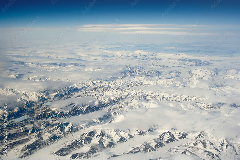 Aerial photography. View of the mountains covered with snow. In the sky above the mountains are clouds. Ilirney Ridge, Chukotka, Siberia, the Far East of Russia. Photo can be used for background.