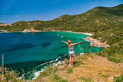 Happy smiling girl standing over the beautiful turquoise lagoon in Corsica