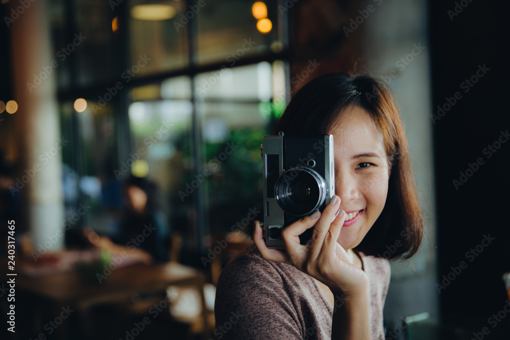 Portrait of pretty young hipster woman taking photo with old vintage film camera.