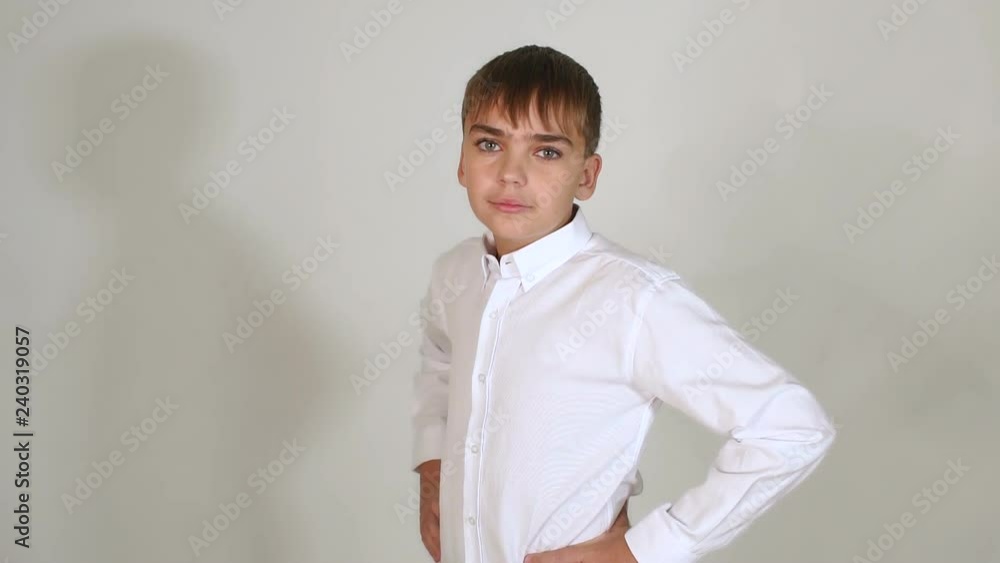 A small dark-haired boy with thick eyebrows posing for the camera in the Studio against a white wall. Portrait of a little boy fashion model. Slow motion. A small dark-haired boy with thick eyebrows posing for the camera in the Studio against a white wall. Portrait of a little boy fashion model. Slow motion.