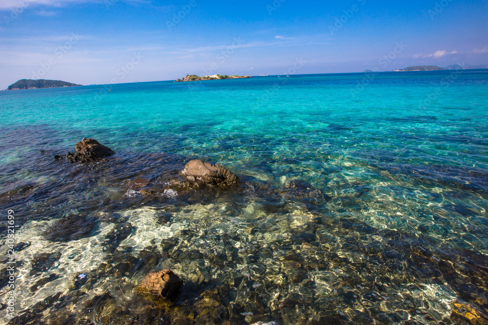 The background of the clear water of the sea, clearly visible sand and rocks, blue sky wallpaper With natural beauty The background of the clear water of the sea, clearly visible sand and rocks, blue sky wallpaper With natural beauty