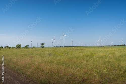 Beautiful landscape with wind generator turbines in green field and blue sky