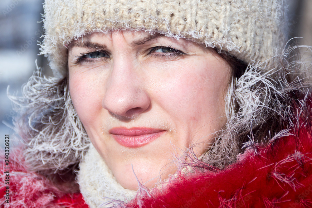 A girl in a red jacket and a white knitted hat in the winter in the cold. Hoarfrost on hair and eyelashes. A girl in a red jacket and a white knitted hat in the winter in the cold. Hoarfrost on hair and eyelashes.