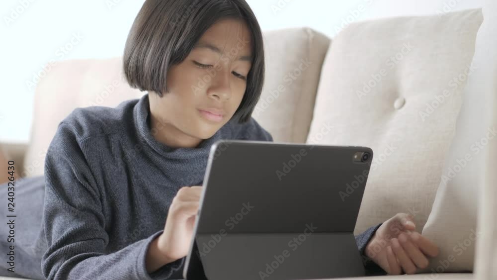 Asian girl using tablet computers for education on sofa Asian girl using tablet computers for education on sofa
