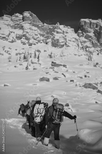 A group of climbers climbs the snow-covered slope. Black and white.