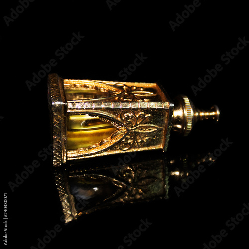 Golden bottle of parfum on black background.