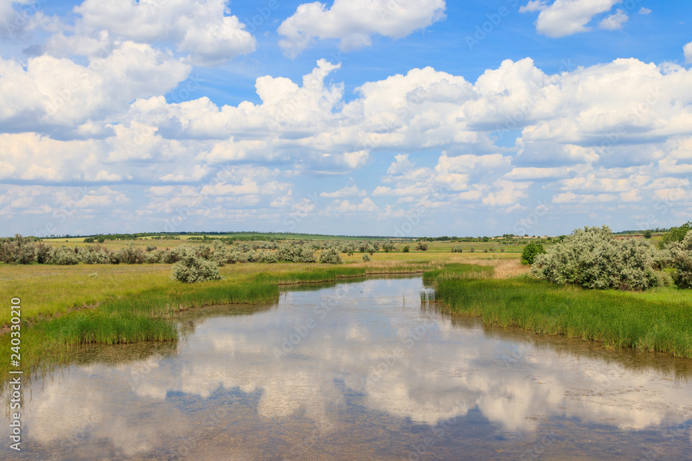 Summer landscape with small river and blue cloudy sky