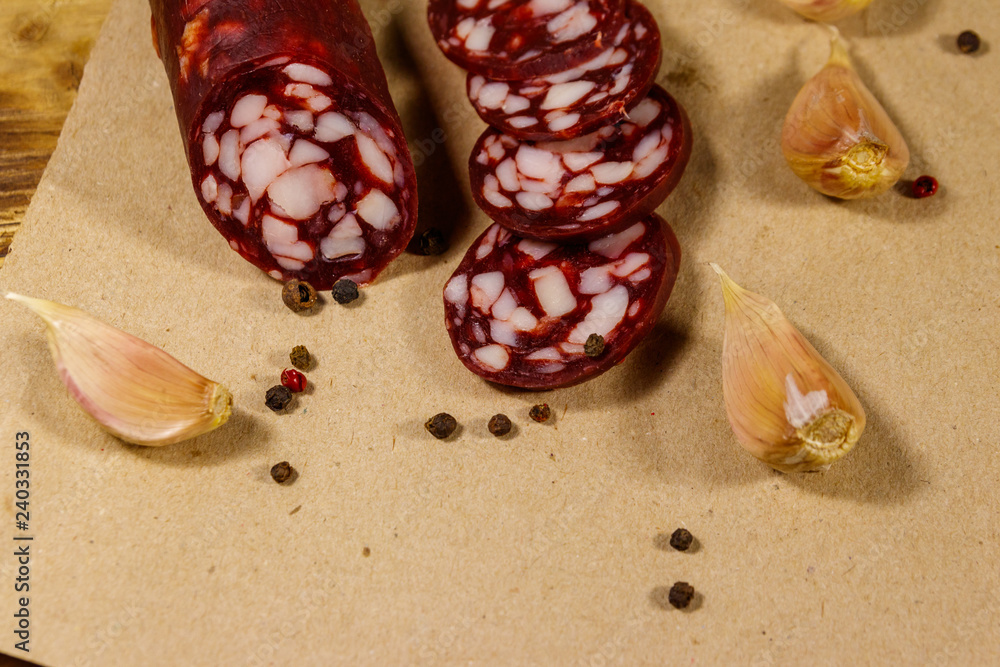 Sliced salami sausage on brown paper on wooden table Sliced salami sausage on brown paper on wooden table