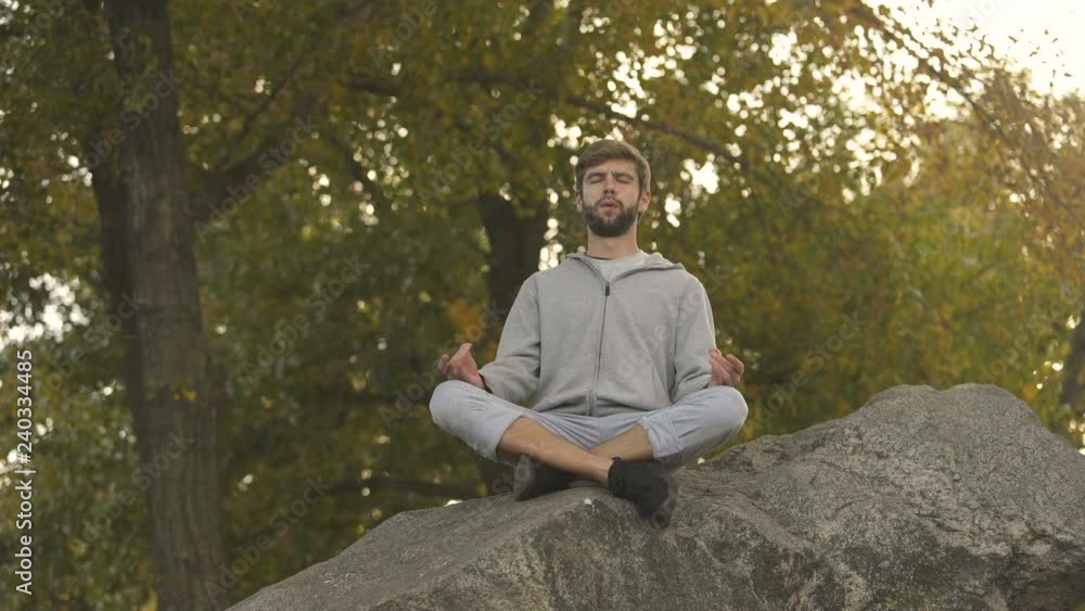 Male doing yoga outdoors, lotus pose, meditating in wild, harmony and balance Male doing yoga outdoors, lotus pose, meditating in wild, harmony and balance