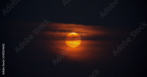 Rising moon through the clouds at dusk