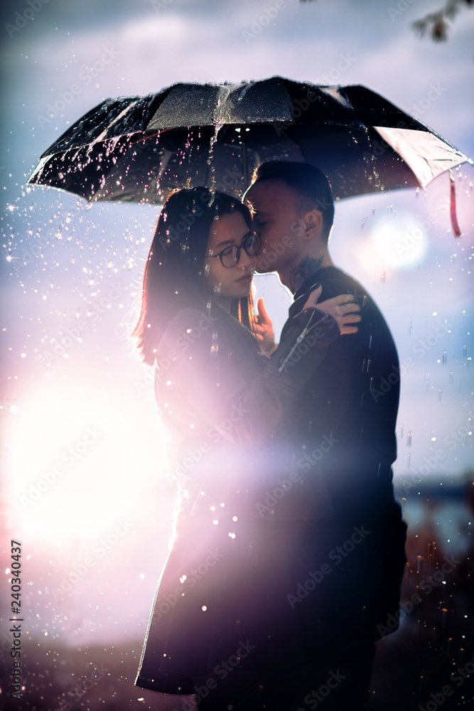 young man and woman under an umbrella and rain