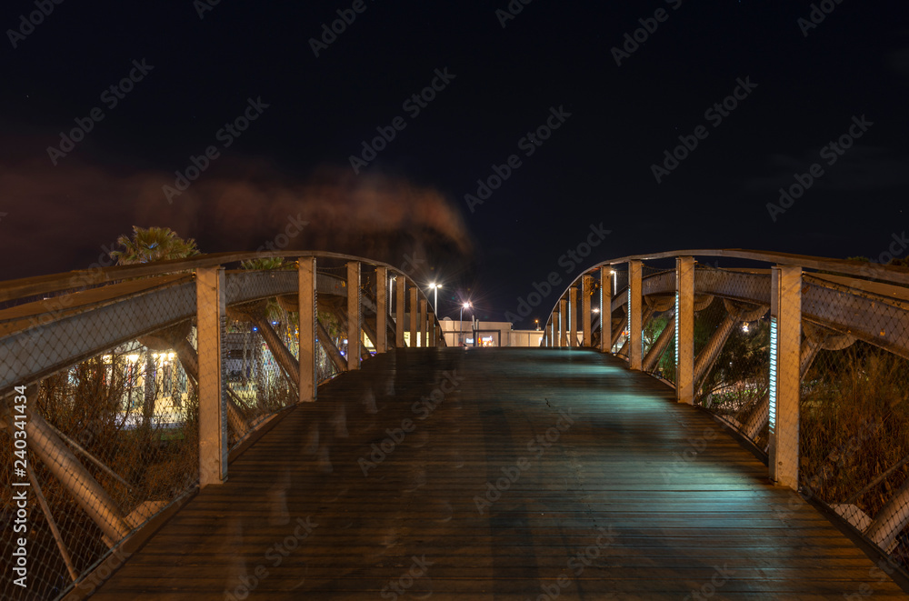 Pedestrian curved bridge over yarkon river at night
