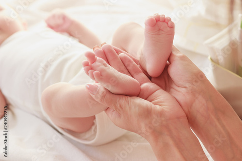 Mother holds feet of her baby in the hands, indoors, blurred background © lisssbetha
