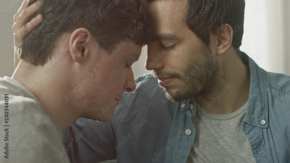 Cute Male Queer Couple Put Their Heads Together and Close Their Eyes. Sweet Gentle Loving Gay Relationship Moment. Room Has Modern Interior. Cute Male Queer Couple Put Their Heads Together and Close Their Eyes. Sweet Gentle Loving Gay Relationship Moment. Room Has Modern Interior.