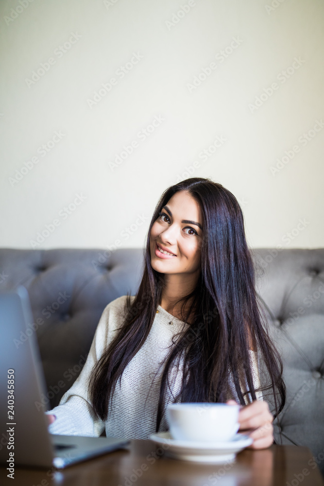 Pretty female student with cute smile keyboarding something on laptop while relaxing after lectures in University. Beautiful happy woman working on laptop computer during coffee break in cafe bar Pretty female student with cute smile keyboarding something on laptop while relaxing after lectures in University. Beautiful happy woman working on laptop computer during coffee break in cafe bar