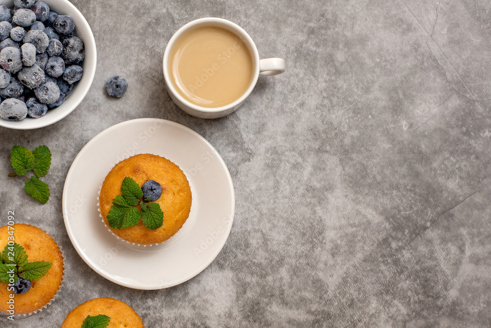Blueberry muffins with cup of coffee on grey background. Top view. With copy space Blueberry muffins with cup of coffee on grey background. Top view. With copy space